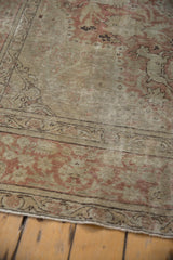 Distressed pile and intricate border of a vintage Kayseri carpet in dusty rose and beige.