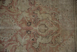 Textured detail of distressed Kayseri carpet with stylized deer, dusty rose, and beige floral elements.