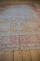 Muted red and gold curvilinear motifs on the worn surface of a vintage Kayseri carpet.