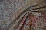 Distressed vintage Turkish Kayseri carpet, showing worn pile, muted red and beige patterns.