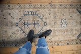 Person's view standing on the vintage Karaja runner, showing its distressed, time-softened texture.