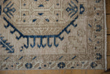 Geometric border patterns in navy blue on the evenly worn, sandy beige pile of a Karaja rug.