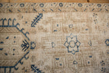 The distressed, low-pile texture of a vintage Karaja runner with navy blue pinwheel designs.