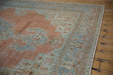Close view of distressed vintage Khoy carpet's fringed edge and worn tangerine, seafoam pile.