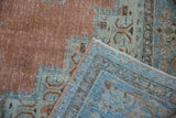 Folded vintage Khoy carpet displaying worn tangerine pile and original blue side selvage.