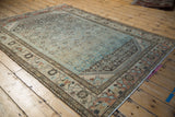Distressed Persian Borchalou rug from an angle, showing its worn texture and pale blue Herati field.