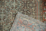 Distressed Persian rug corner folded to display the low pile and hand-knotted back weave.
