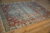 Distressed Bakhtiari rug corner with geometric vinery, faded cherry red, powder blue, and blush.