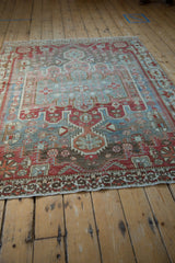 Distressed Bakhtiari rug texture, with faded geometric vinery and floral motifs in dusty blue, red, ivory.