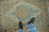 Distressed blue and apricot diamond medallion with arrowed finials on an abrashed vintage Bibikabad rug.