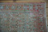 Distressed Malayer rug corner, muted powder blue and brick red patterns, fringe.