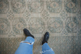Distressed Ersari carpet texture featuring muted cream and dusty teal geometric guls.