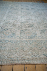 Distressed short pile and geometric border details in cream, beige, and dusty teal.