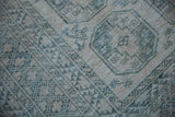 Distressed geometric patterns with serrated relief and short pile in cream and dusty teal.