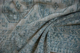 Folded vintage distressed Ersari rug with cream, beige, and dusty teal geometric patterns.