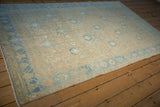 Low angle view across the distressed pile of a vintage Hamadan rug showing its sand and blue tones.