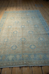 Angled view of a vintage Hamadan rug showing its time-softened sand and powder blue palette.