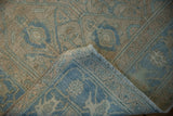A folded corner of the distressed Hamadan rug reveals its hand-knotted foundation.