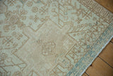 Distressed vintage Karaja rug detail with worn beige geometric patterns and subtle powder blue accents.