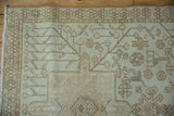 Distressed Karaja rug's beige field showcasing brown vinery and scattered plant motifs with powder blue.