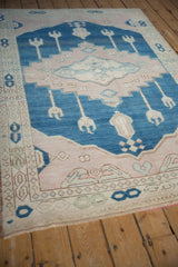 Distressed Oushak rug's short pile, dusty cobalt blue and pale mauve field, stylized blossoms.