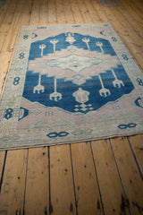 Secured end of vintage Oushak rug with short fringe, displaying pale mauve and blue tones.