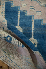 Curved distressed Oushak rug detail: dusty cobalt blue, pale mauve, ivory stepped pattern.