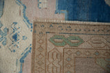 Hand knotted back of the distressed Oushak rug, showing green pattern and intact side cord.