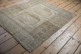 Vintage distressed Ersari rug corner, highlighting geometric border motifs and softened beige tones.