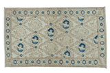Distressed vintage Turkish Sparta rug with ivory field, navy blue floral lattice, and bird motifs.