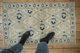 Distressed Sparta rug corner with navy bird and blossom panels, tan lattice, and soft pile wear.