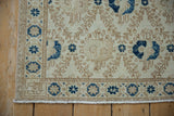 Distressed Turkish Sparta rug corner with ivory, tan lattice, and navy blue bird motif.