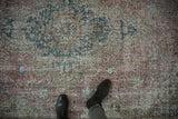Worn texture and muted floral design of a vintage overdyed Sparta carpet in dusty raspberry and blue.