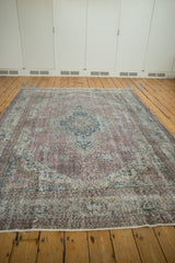 Distressed pile showing faded dusty raspberry and navy floral motifs of Sparta rug.