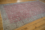 Distressed vintage Sparta carpet corner, showing muted cochineal red, silver, and green vinery.