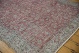 Faded cochineal red floral vinery on distressed vintage Sparta carpet with muted border.