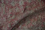 Distressed texture of vintage Sparta carpet in muted cochineal red and ivory.