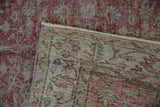 Distressed vintage Sparta carpet corner showcasing worn cochineal pile, patterned foundation, and fringe.