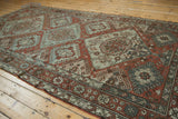 Angled view of a vintage Soumac carpet's distressed geometric field in copper and dusty blue.