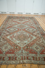 Low angle perspective of the repeating medallions on a vintage distressed Soumac design carpet.