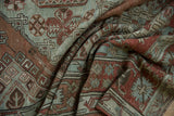 Textured weave and geometric motifs of a distressed Soumac carpet shown in soft, draping folds.