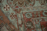 Folded corner of a distressed vintage carpet reveals its hand-woven construction and storied texture.