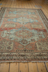 Vintage distressed Soumac design carpet showing repeating wave border and muted blue, terracotta hues.