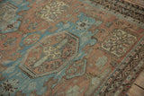 Distressed Soumac design rug with a geometric reciprocating wave border in terracotta and blue.
