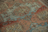Distressed Soumac rug, stylized pinwheel and geometric gul motifs in blue and terracotta.