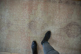 Distressed Oushak rug runner with worn texture and faded ivory, blush geometric patterns.