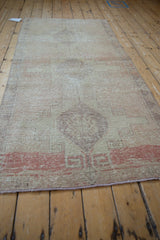 Distressed pile texture and geometric hook-and-latch motifs in ivory and blush on Oushak rug.
