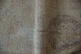 Distressed Oushak rug close-up shows worn pile, exposed foundation, and muted geometric patterns.