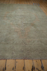Distressed vintage Oushak rug showing faded sage green, dusty sandalwood, and abrashes.
