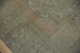 Distressed Oushak rug with abrashes, showing pale sage green and dusty sandalwood wear.